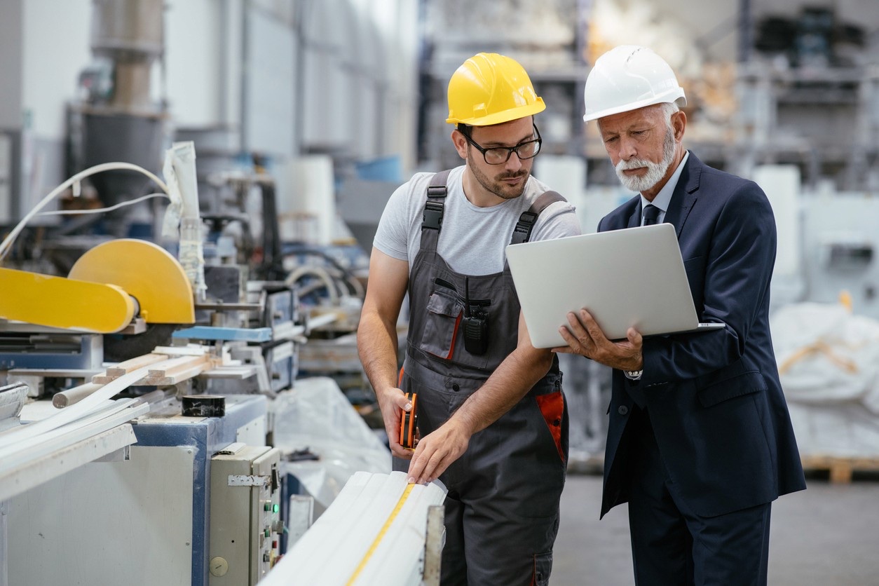 Techniker und Geschäftsführer prüfen gemeinsam Produktionsdaten in einem Kunststoffwerk